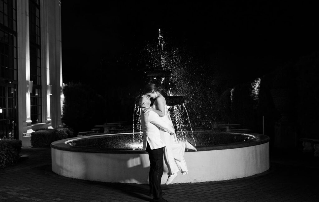 Outdoor nighttime picture of bride and groom near the fountain at The Addison Park